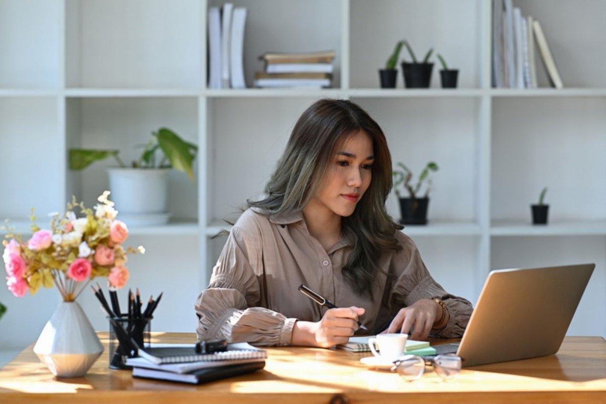 Woman planning her week at a desk with a notebook and laptop